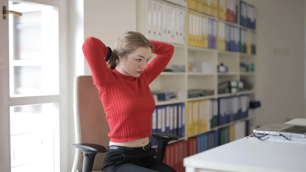 勉強の合間にデスクで伸びをする女性